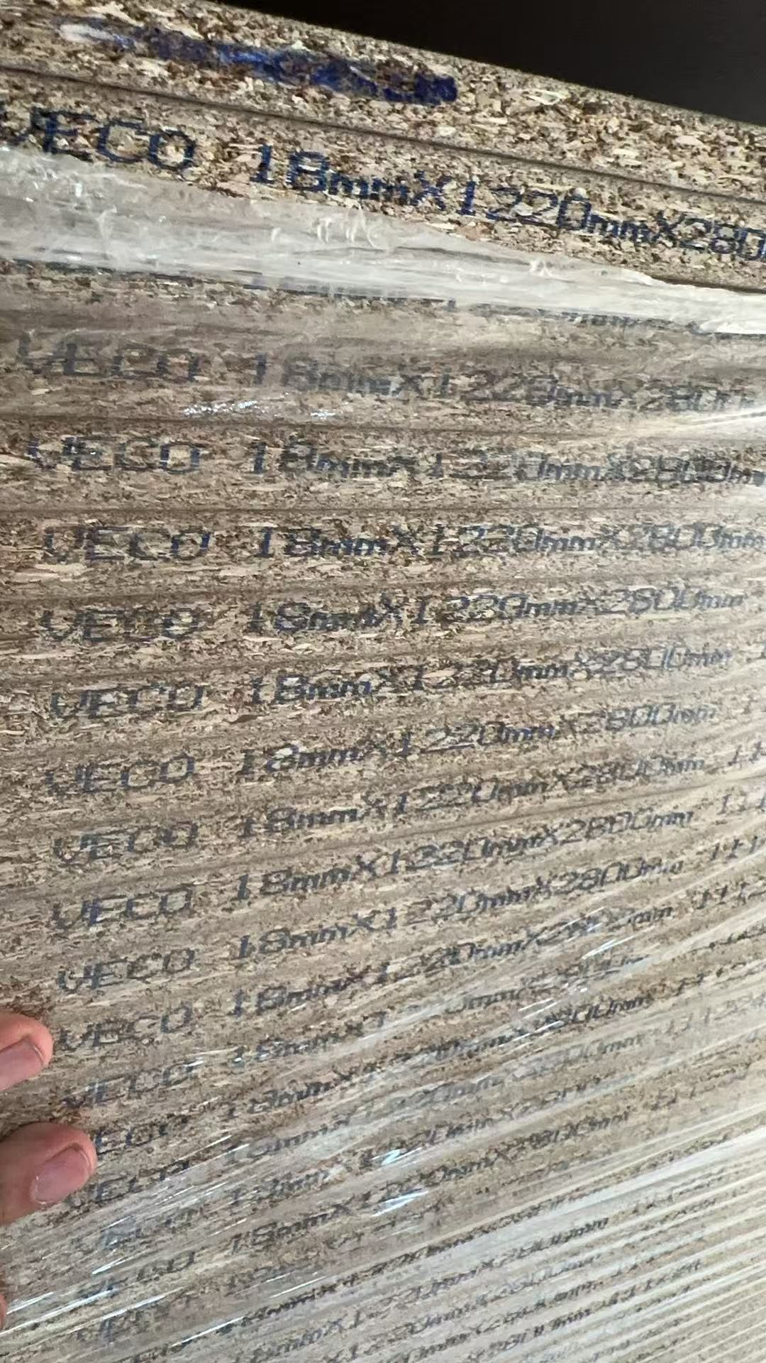 堆叠的刨花板基材短边上可见 VECO 及板材规格喷码